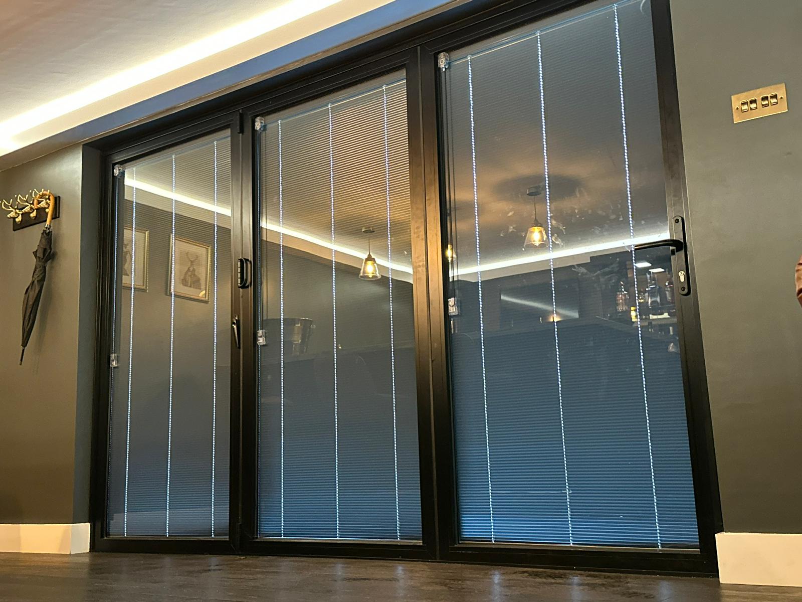 Close-up of aluminium bi-fold door bottom track and roller mechanism, brushed metal finish, gasket seals visible